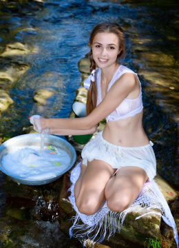 Девушка оставляет за собой водную пену, пока она стирает белье в ручье