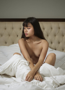 Азиатская девушка с маленьким размером груди лежит на кровати