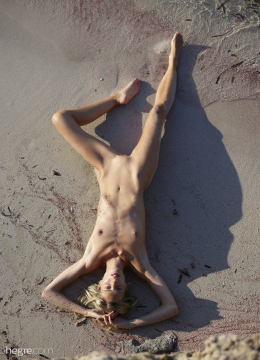 Тонущая в песке на пляже, девушка с худощавыми ножками